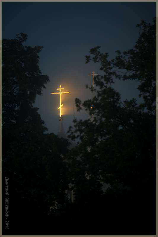 Церковный крест в лучах рассвета сквозь туман
